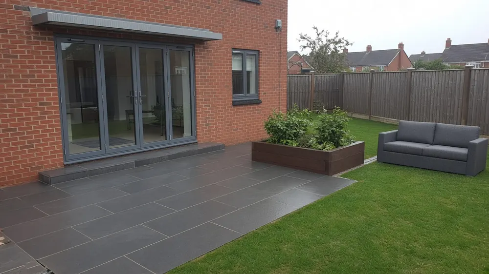Example image: a charcoal porcelain patio outside bi-fold doors on a modern estate house
